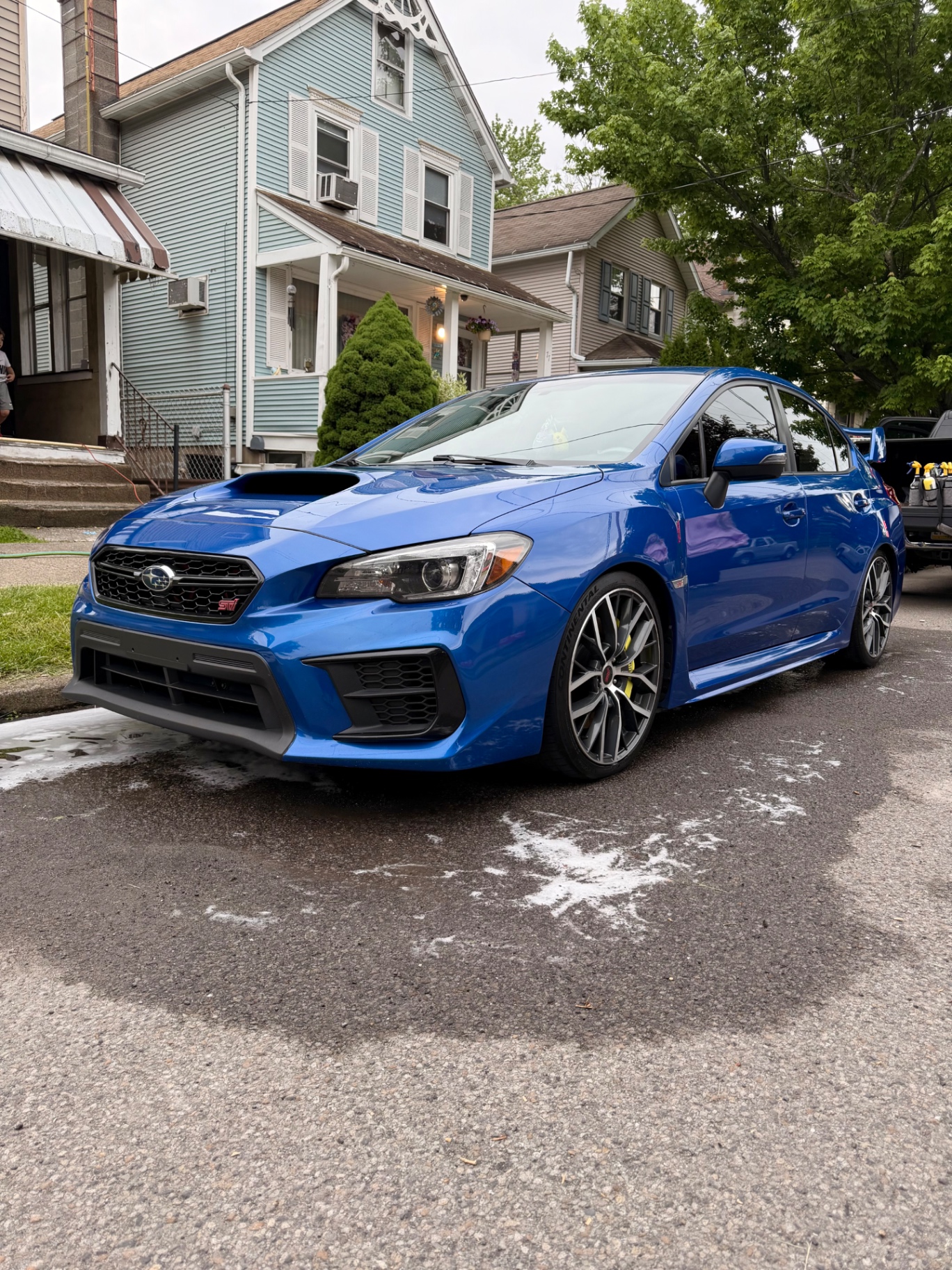 Blue Subaru WRX STI front three-quarter during wash